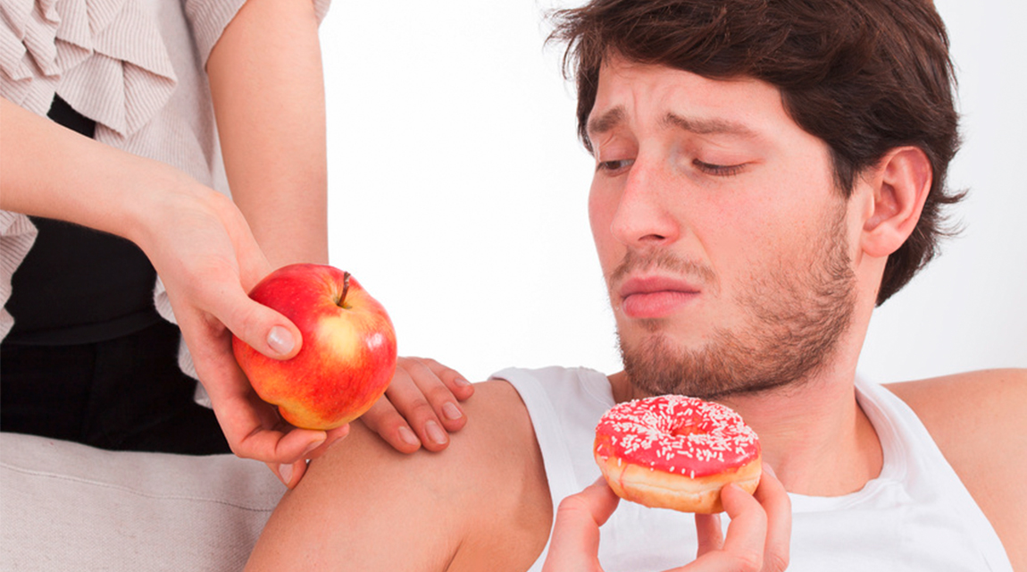 Mann hält einen Donut in der Hand und bekommt einen Apfel angeboten