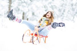 glückliche Frau fährt Schlitten durch den Schnee