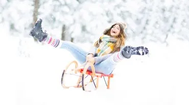 glückliche Frau fährt Schlitten durch den Schnee