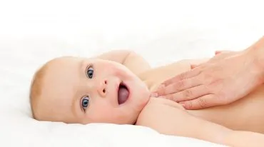 Baby wird mit Pflegeöl massiert und grinst