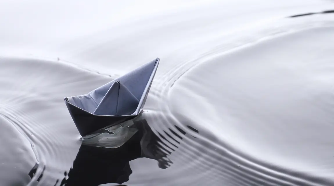 Papierschiff auf ruhigem Wasser